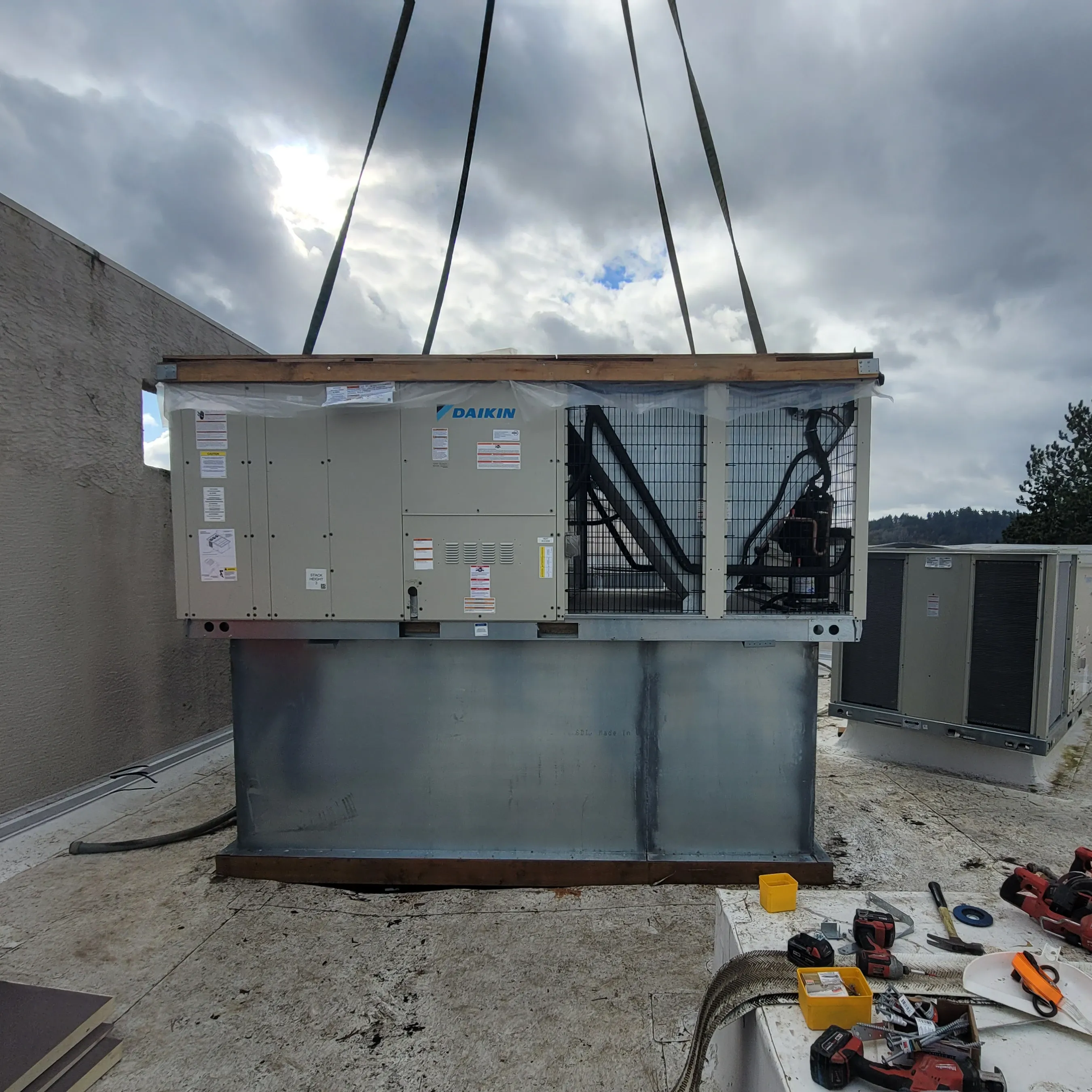 Commercial rooftop HVAC unit being lowered onto its curb