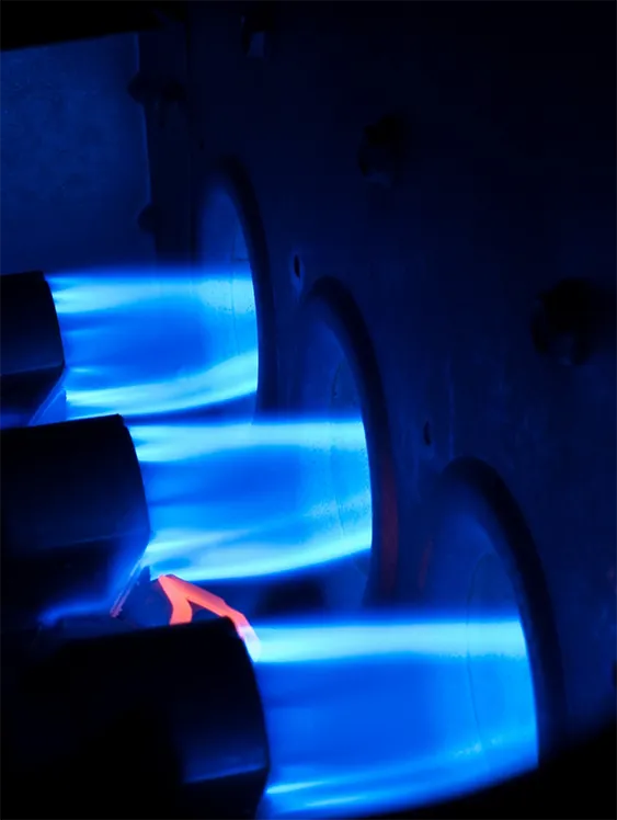 Close-up of a gas furnace's burners running with a clean blue flame