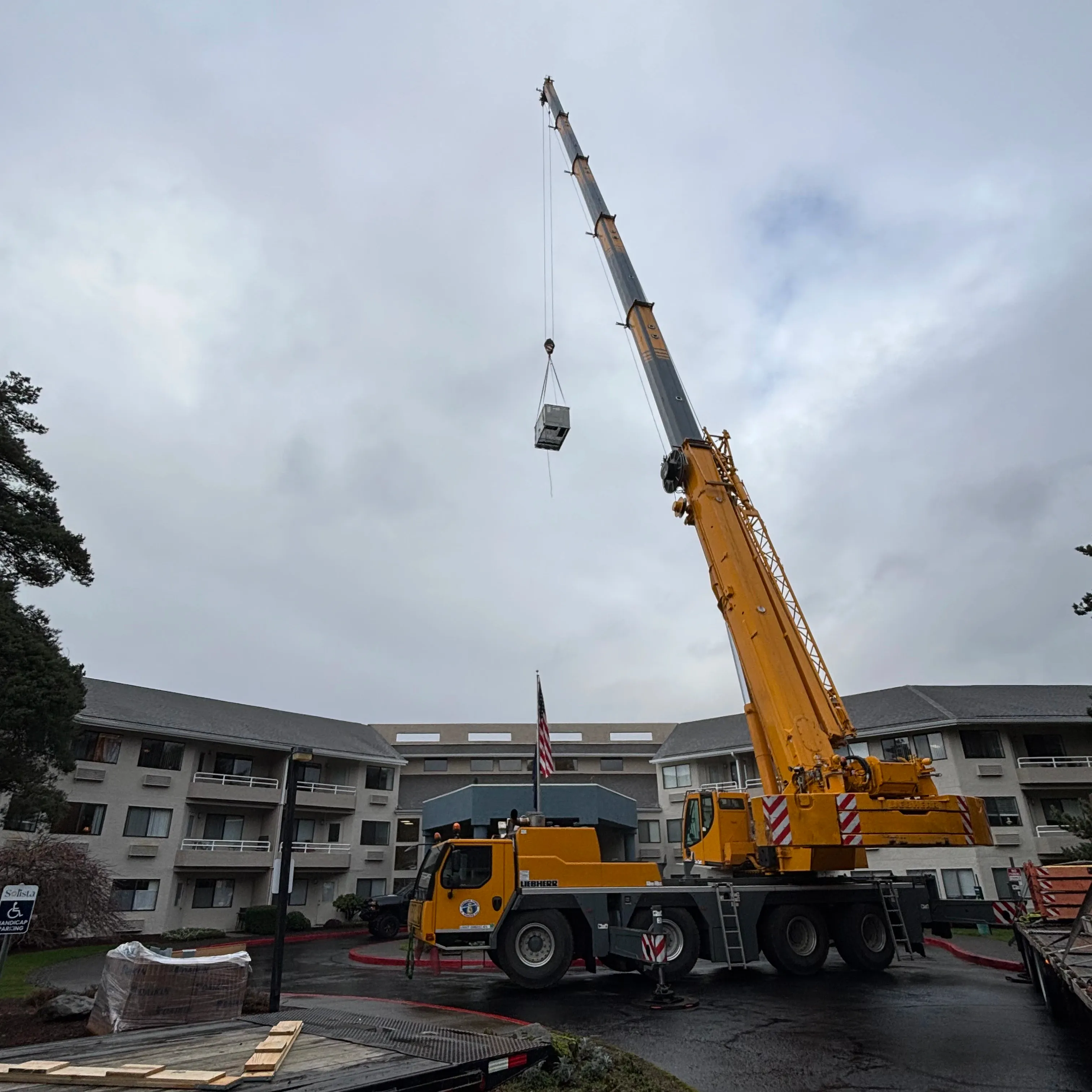 Crane lifting a commercial rooftop HVAC unit into place