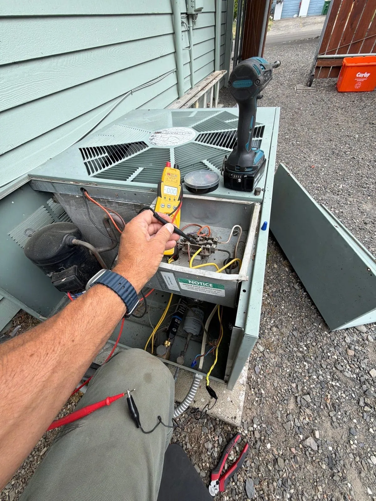 A Comfy technician testing an air conditioner's contactor and capacitor with a multimeter