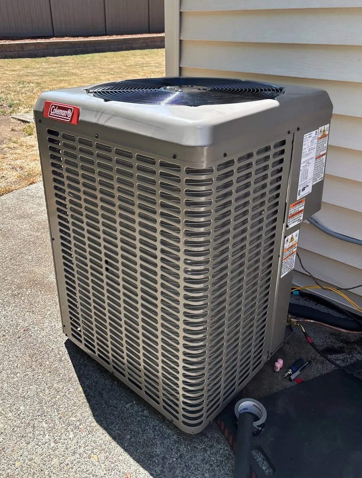 A newly installed air conditioner condenser beside a home