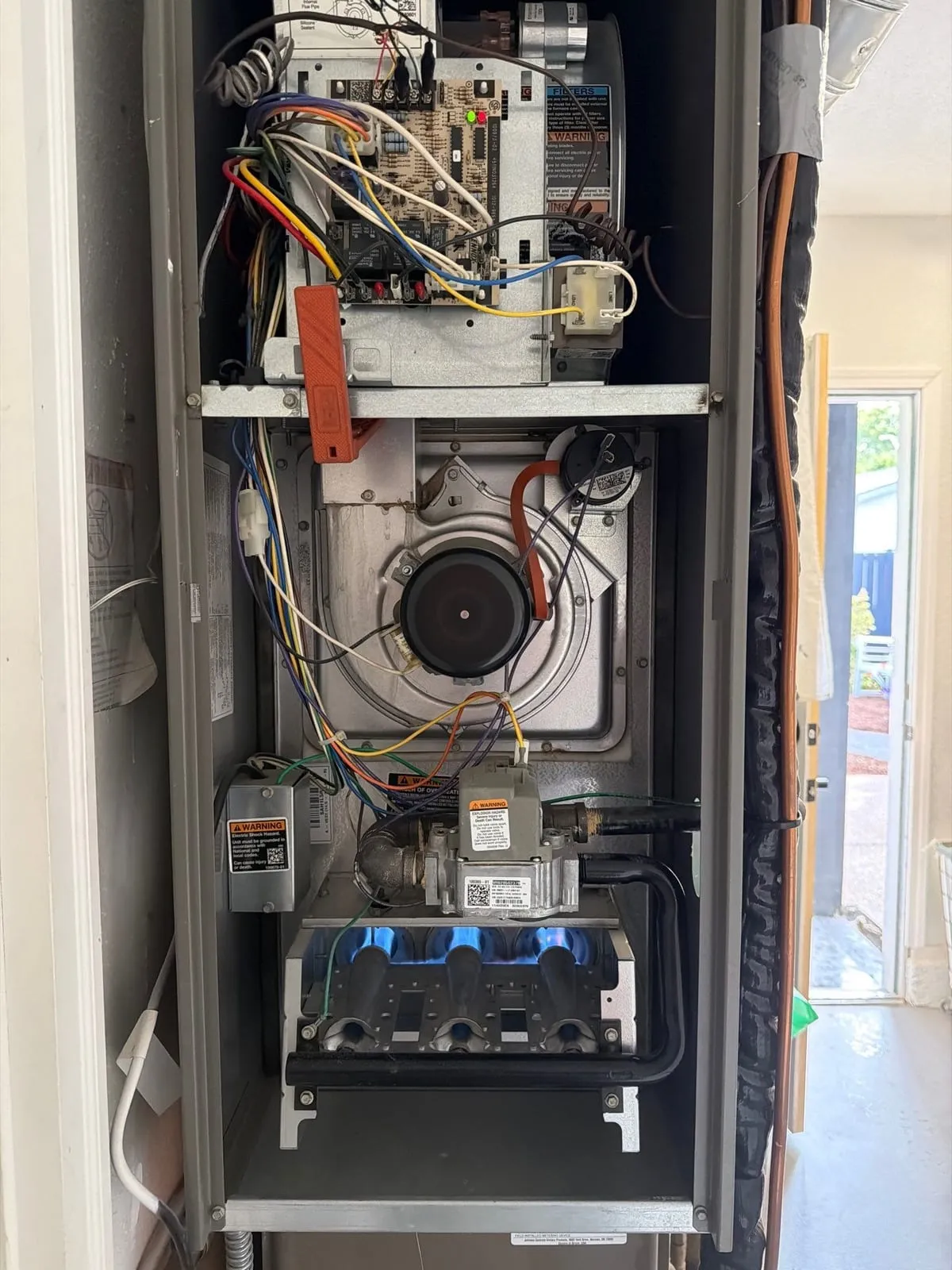 An open gas furnace with its burners lit during a service check